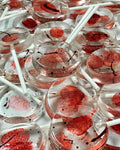 Clear round lollipops with red edible fingerprints and blood spatter on white sticks.